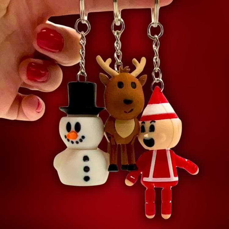 Snowman, reindeer and elf keychains held in a hand